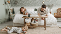 A joyful family bonding in a cozy bedroom, featuring a playful child and loving parents.