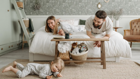 A joyful family bonding in a cozy bedroom, featuring a playful child and loving parents.